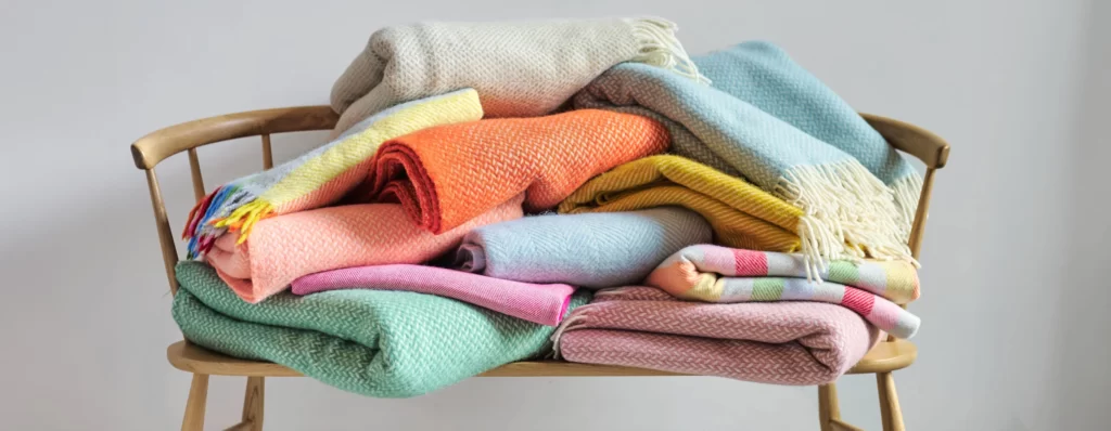 A vibrant stack of blankets rests on a wooden chair.