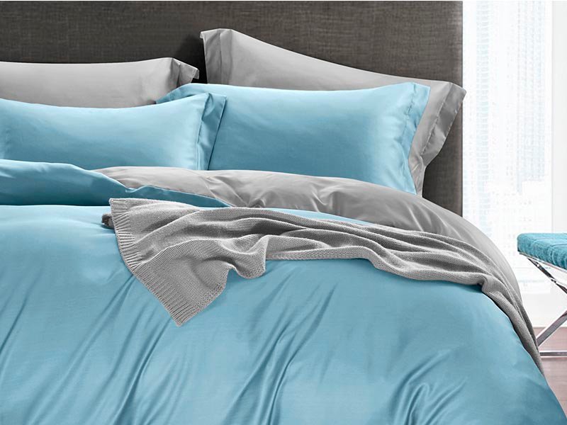 A blue and gray comforter with a matching gray pillow, providing a cozy and stylish bedding arrangement.