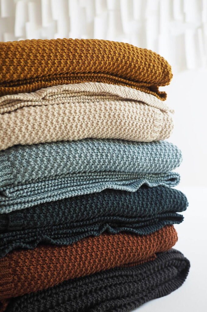 A stack of blankets, showcasing a variety of vibrant colors.