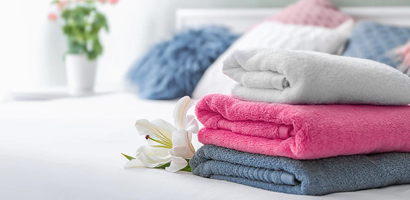 Towels neatly stacked on a bed adorned with flowers.
